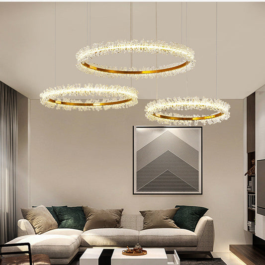 Three gold ring crystal chandeliers hanging at different heights above a living room sofa